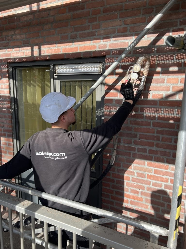 Technicus voert isolatie aan de buitenmuur van een woning in Eindhoven uit, gericht op energiebesparing en woningisolatie met isolatieschuim en parels.
